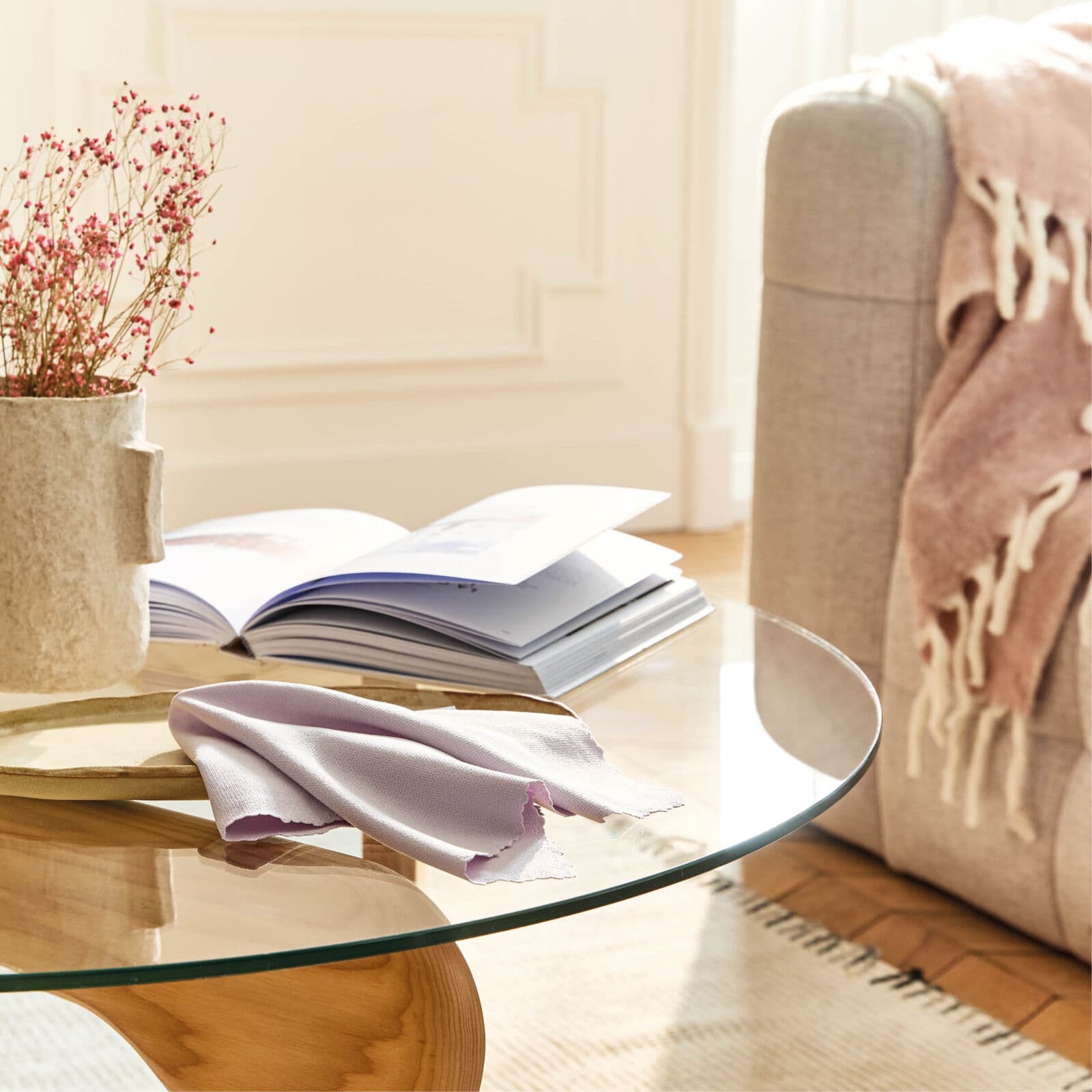 Chiffon spécial vitres H2O at Home posé sur une table en verre, reflétant un intérieur cosy avec livres ouverts et décoration naturelle