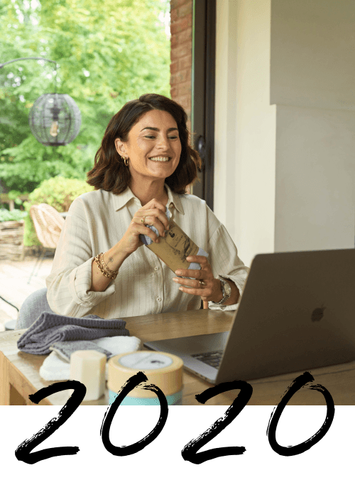 Photo d'une conseillère H2O at Home montrant le kit signature à la caméra durant un atelier à distance avec l'année "2020" mentionnée par-dessus la photo